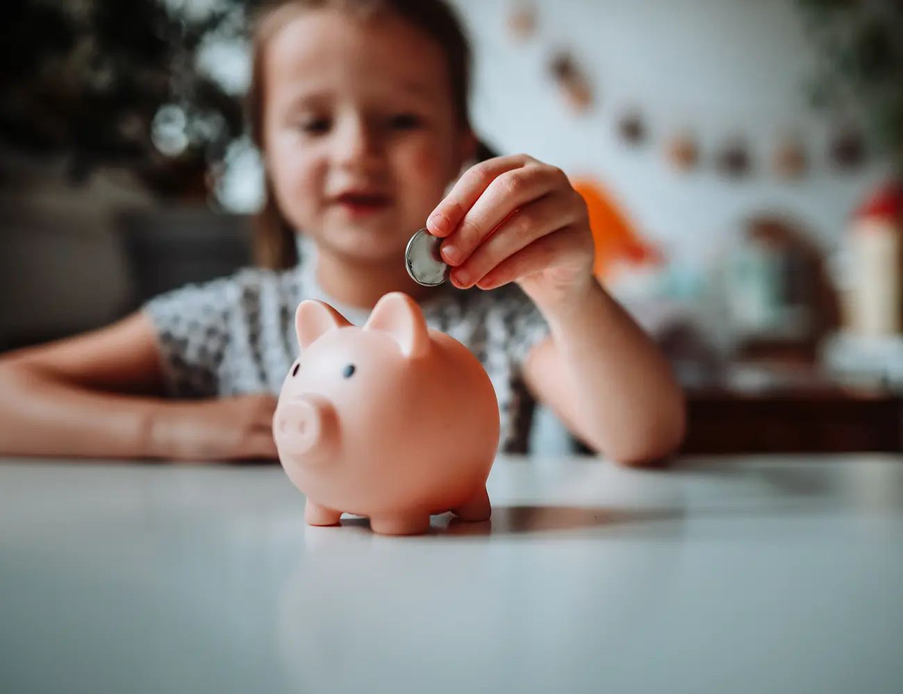 girl putting coin in piggy bank